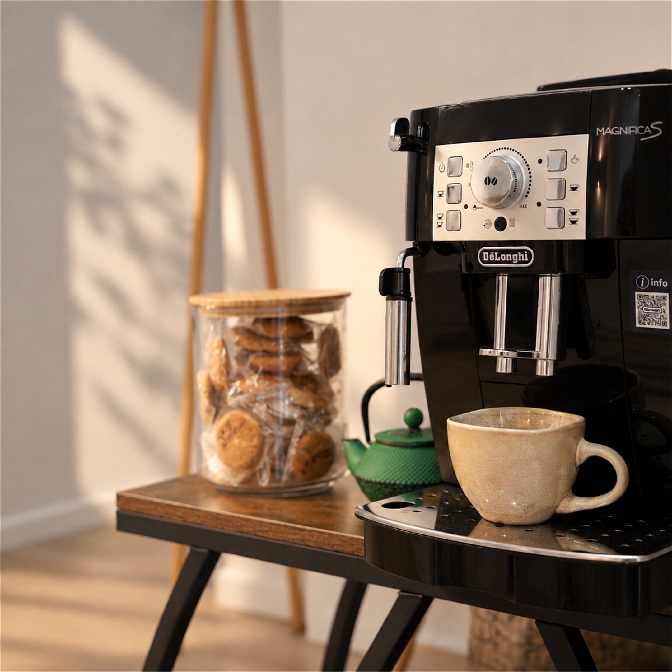 Cafetera espresso con una taza de gres, un tarro de galletas y una tetera de hierro fundido verde