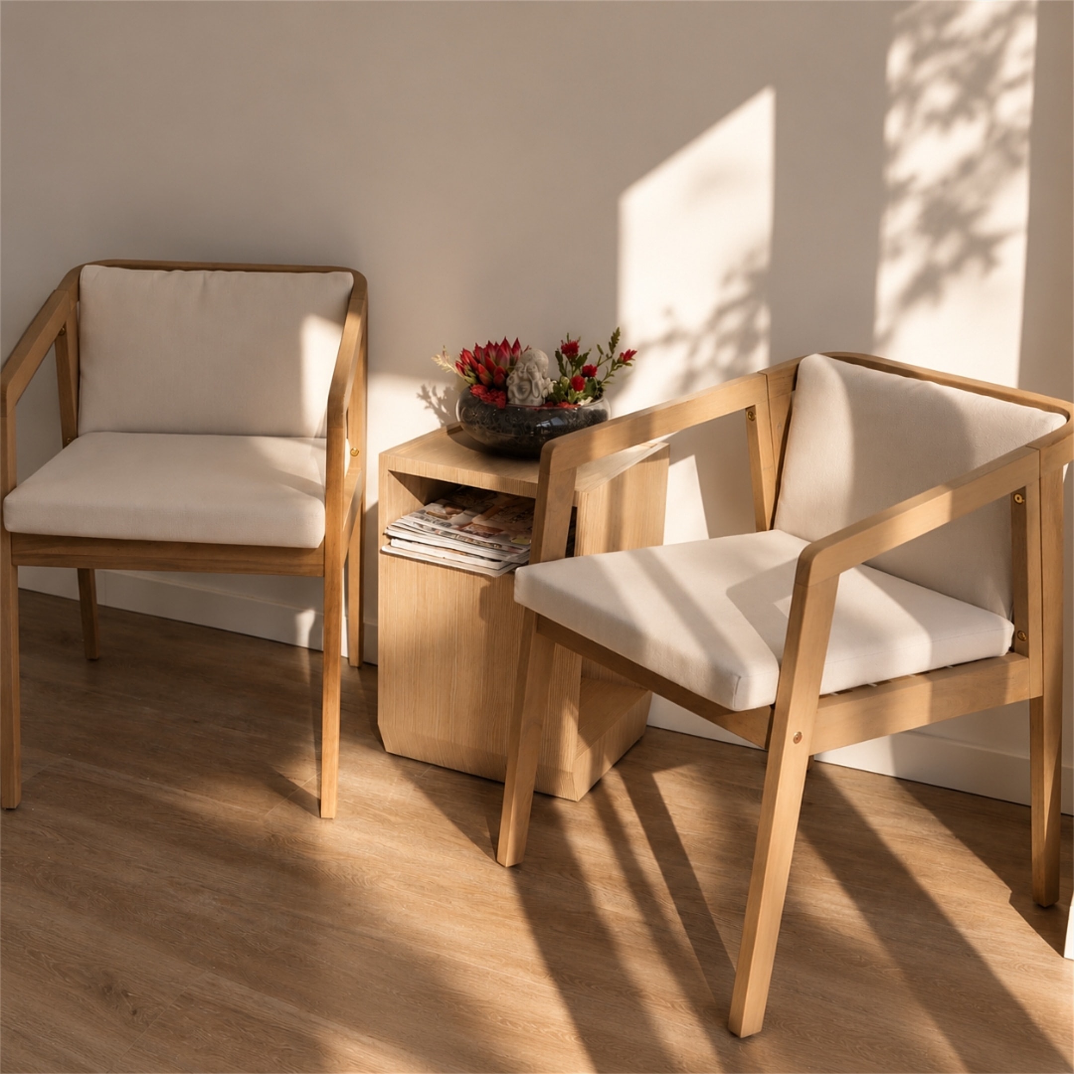 Dos sillones de madera con cojines crudos junto a una mesita en la zona de recepción
